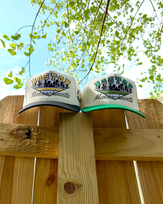 Retro Boston Snapback - The Bird caps, featuring vintage skyline embroidery, rest on a fence post; perfect for representing Boston and the Celtics.