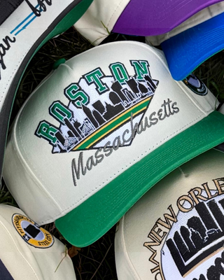 Boston Snapback - The Bird: Retro-style cap with BOSTON and skyline embroidery, evoking vintage Celtics pride. Perfect for representing Boston in a classic throwback design.