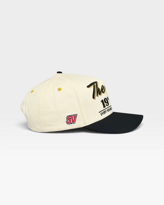 The 19th Hole Snapback (Cream/Black) features a retro two-tone design with embroidered logos, capturing the fun, relaxed spirit of the 19th hole in golf.